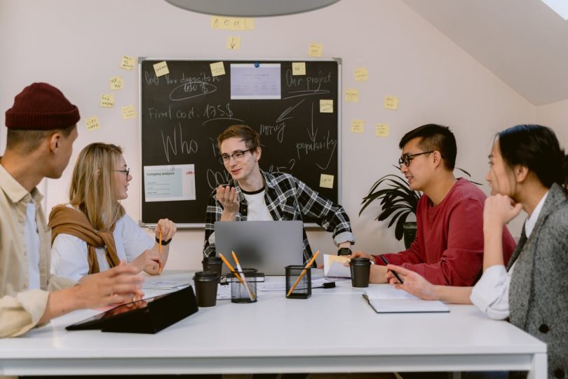 four people sitting around table and discuss about work